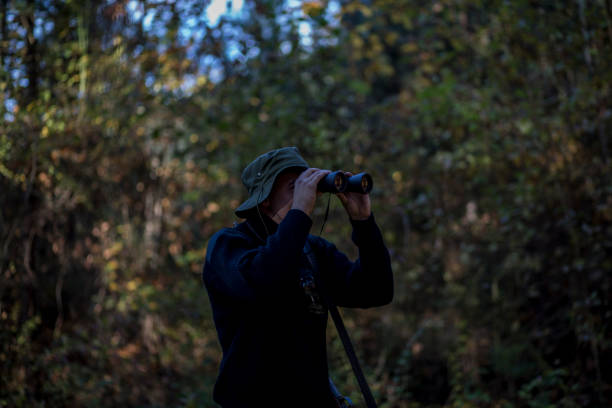 istock Man in the woods watching through his binoculars 866567192
