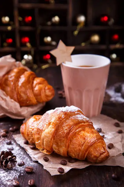 Christmas or New Year pastries,Croissant with a warming drink,coffee.Winter Holidays Concept.Holiday Decorations. top view.Vintage style. selective focus.