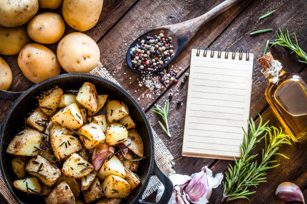 Roasted potatoes with cookbook on wooden kitchen table