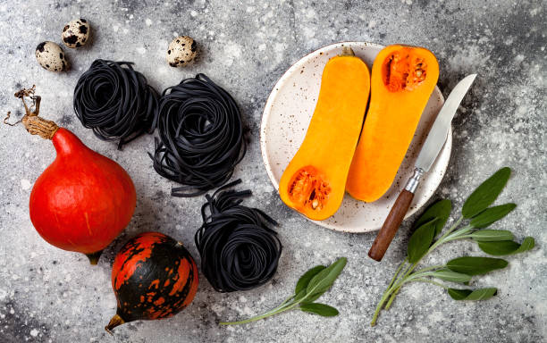 istock Raw ingredients for making black pasta with butternut squash, parmesan cheese and sage. Concrete background, top view, flat lay. Halloween black and orange party dinner concept 866605198