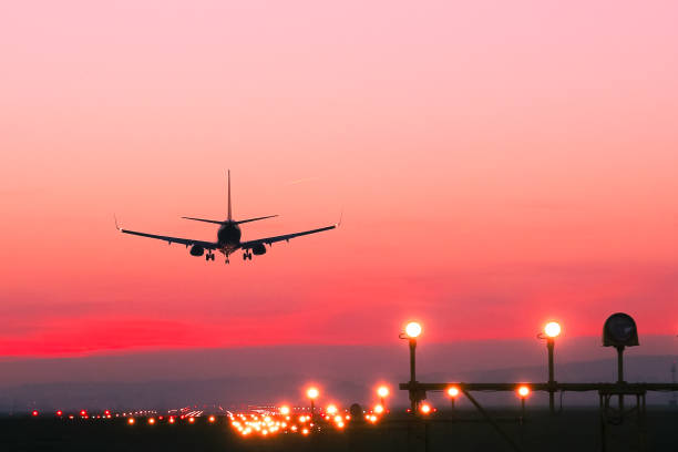 avión aterriza en un campo de aviación en la puesta del sol - aterrizar fotografías e imágenes de stock