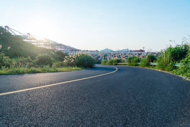 istock empty highway with an industrial port on background 866637766
