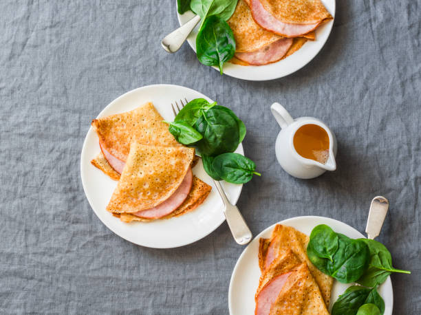 Crepes with ham and spinach. Delicious, nourish breakfast on a grey background, top view Crepes with ham and spinach. Delicious, nourish breakfast on a grey background, top view nourish stock pictures, royalty-free photos & images