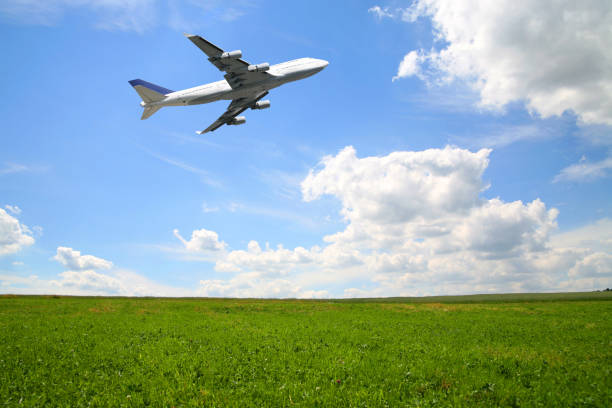 Huge airliner taking off in summer nature scene with green lawn and blue and white sky