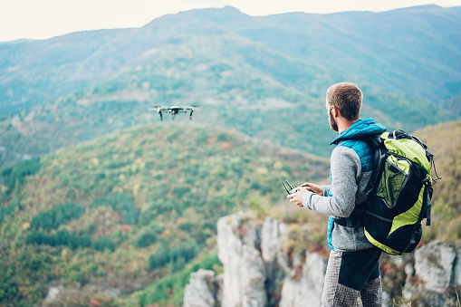 Backpacker flying a drone in the mountain