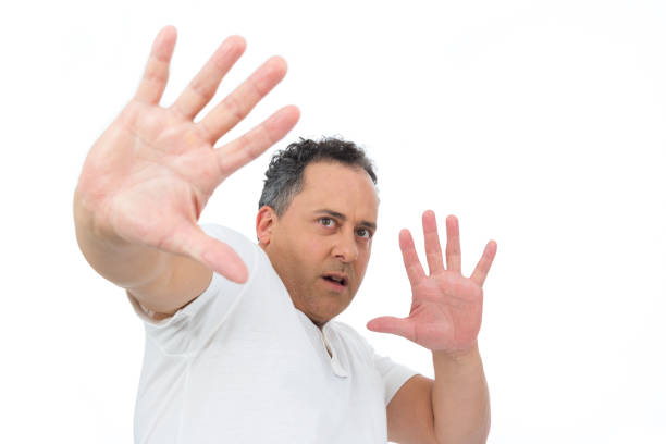 istock Man gestures scared. He is overweight and is wearing a white polo.