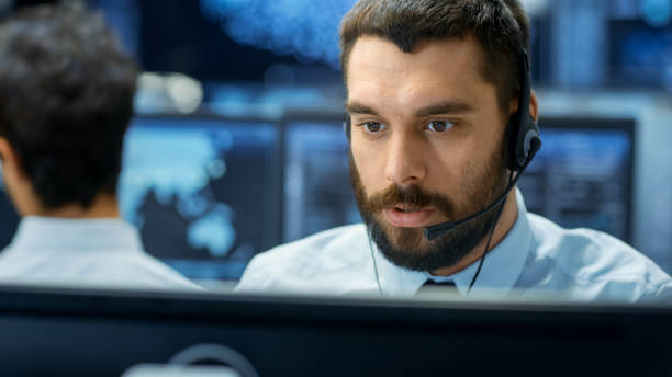 istock Customer Service Representative Answer Client's Questions in a Headset. He Works for a Big Technological Company. Office Has Multi-Ethnic Team of Specialists, Displays Show Useful Information. 866661178