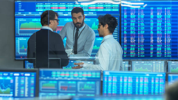 istock Three Experienced Stock Traders Talking Business. They Work for a Big Stock Exchange Firm. Office is Full of Displays Showing Data, Infographics and Numbers. 866662168