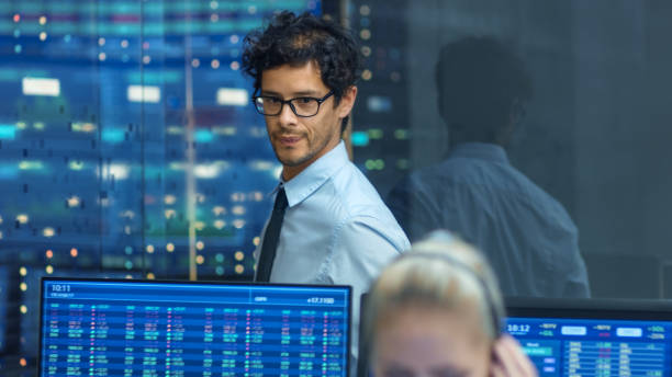 istock Stock Trader Inspects Others Work and Chat with Other. Busy Office with Multi-Ethnic Team of Brokers, Dealers. Displays Show Numbers and Infographics. 866662220