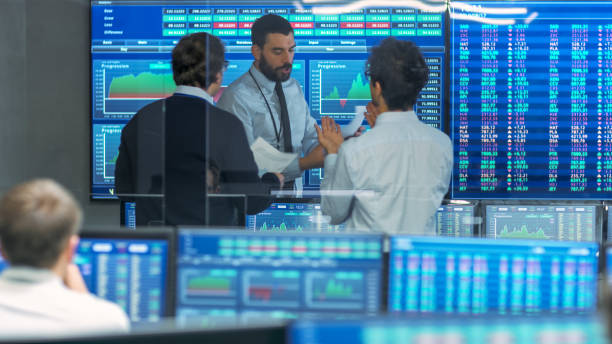 istock Three Experienced Stock Traders Talking Business, Consulting Documents and Argue About Data. They Work for a Big Stock Exchange Firm. Office is Full of Displays Showing Infographics and Numbers. 866662262
