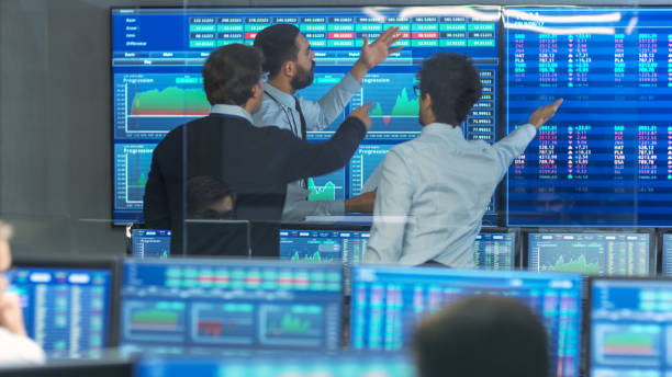 istock Three Experienced Stock Traders Talking Business, Consulting Documents and Argue About Data. They Work for a Big Stock Exchange Firm. Office is Full of Displays Showing Infographics and Numbers. 866662292