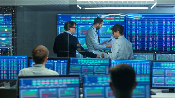 istock Three Experienced Stock Traders Talking Business, Consulting Documents and Argue About Data. They Work for a Big Stock Exchange Firm. Office is Full of Displays Showing Infographics and Numbers. 866662308