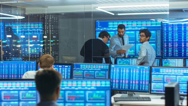istock Three Experienced Stock Traders Talking Business, Consulting Documents and Argue About Data. They Work for a Big Stock Exchange Firm. Office is Full of Displays Showing Infographics and Numbers. 866662322