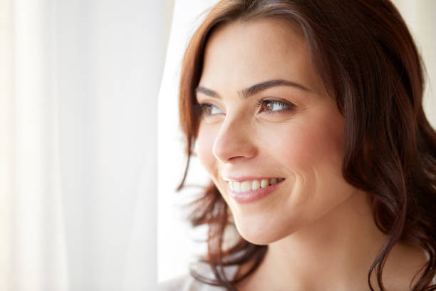 istock happy young woman looking through window at home 866662434
