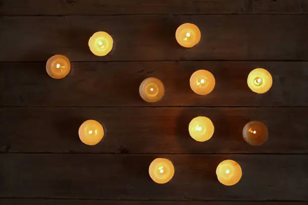 Small round tea light candles on wooden table top view.