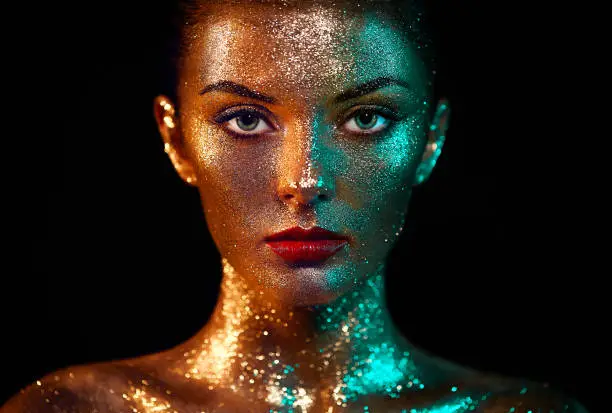 Portrait of Beautiful Woman with Sparkles on her Face. Girl with Art Make-Up in Color Light. Fashion Model with Colorful Makeup