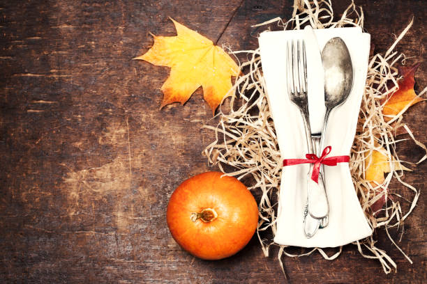 istock Dinner plate setting top view with Thanksgiving decorations on old wooden table. Seasonal cutlery on Autumn background.
