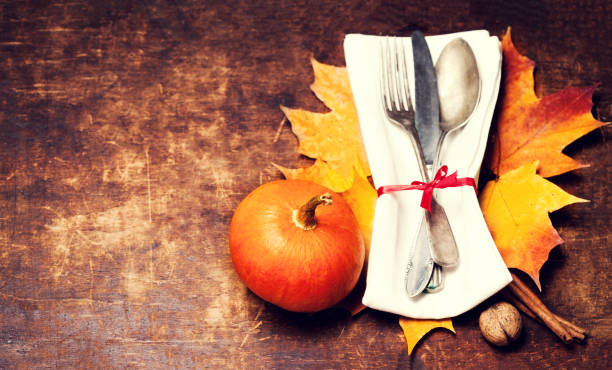 istock Dinner plate setting top view with Thanksgiving decorations on old wooden table. Seasonal cutlery on Autumn background.