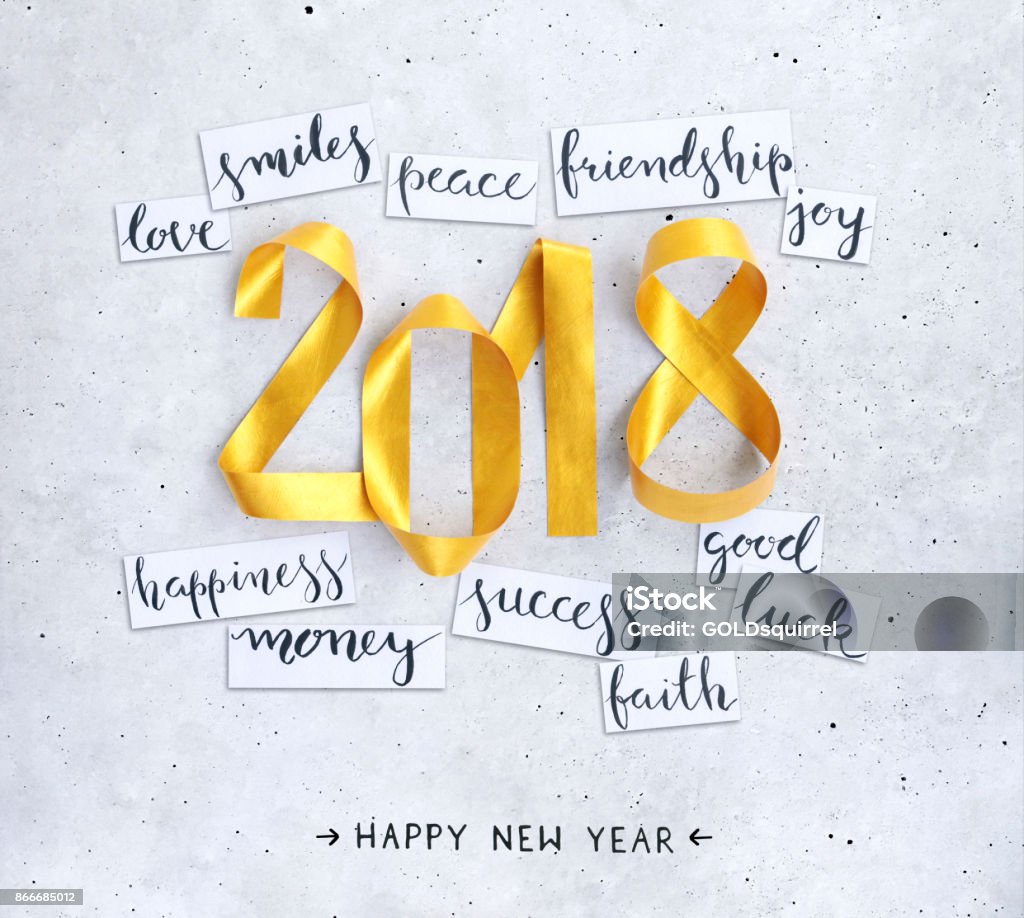New Year's handwritten wishes on strips of white paper lying on a concrete background New Year's handwritten wishes on strips of white paper lying on a concrete background. Square composition with gold paper strips bent in 2018 shape. Beautiful and original design. 2018 Stock Photo