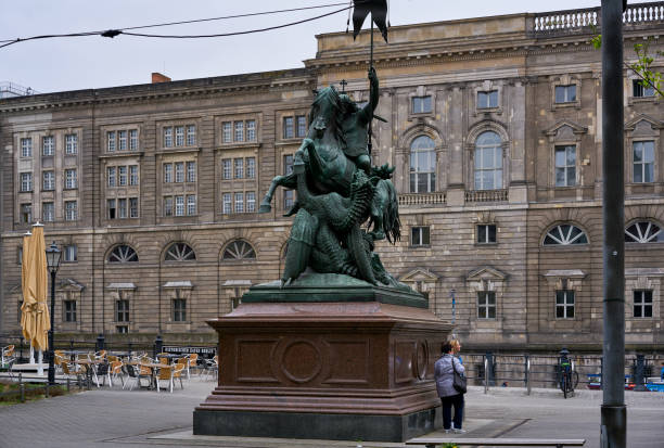 Berlin - The bronze sculpture by Christian Friedrich Tieck (19. cent.) in front of  Konzerthaus building on the Gendarmenmarkt square and German Dom in the background.