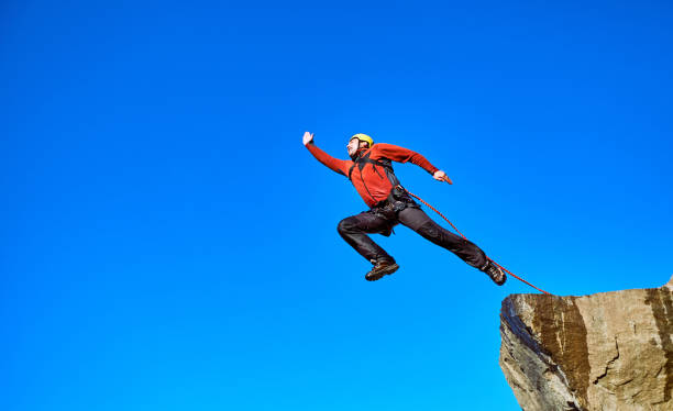 Jump off the cliff with a rope. Man jumping off a cliff with a rope on a sunny day. bungee jumping stock pictures, royalty-free photos & images