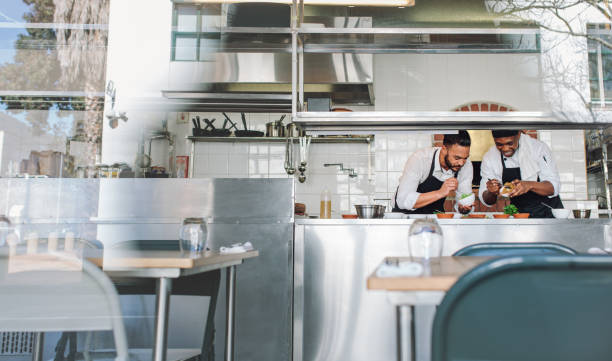 Two male chefs cooking food together at restaurant kitchen. Professional cooks making food dish at restaurant kitchen together.
