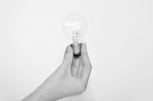 istock female hand holding a light bulb, black and white, lightning 866699554