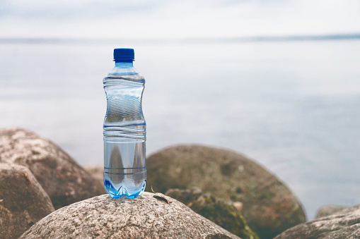 Small water bottle on the ocean stone in natural background.