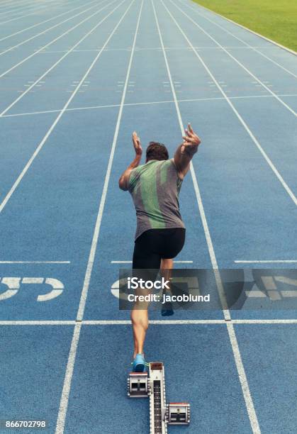 Sprinter Taking Off From Starting Block On Running Track Stock Photo - Download Image Now