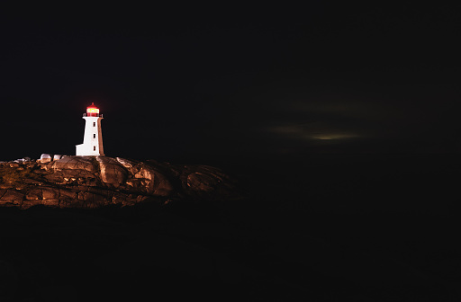 Peggy's Cove Lighthouse shines in the black of night.  Long exposure.