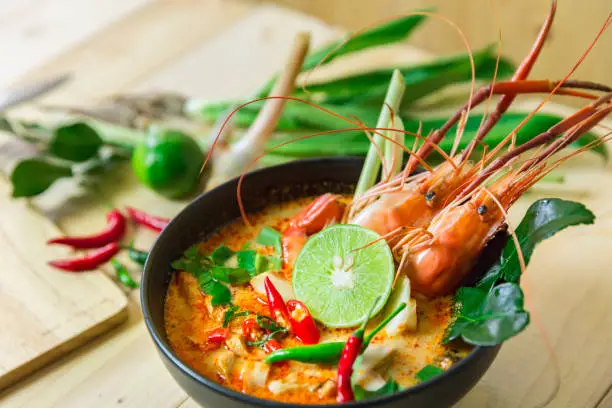 Top view "Tom Yum Kung" on wooden background, It's local in Thai food, Prawn soup is popular and famous food, I'ts delicious amazing taste hot and spicy.