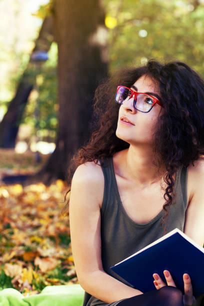 istock Student girl reading a book in the park 866734680