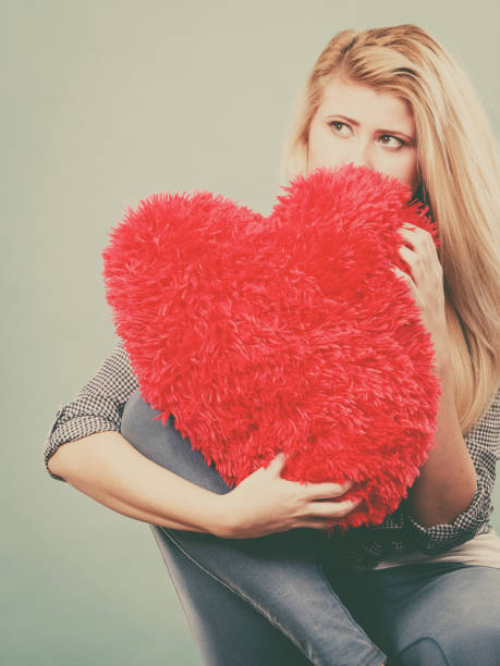 istock Sad woman holding red pillow in heart shape 866740020