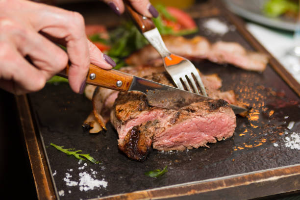 mano de mujer sosteniendo el cuchillo y el tenedor corte a la parrilla bistec - steak grilled beef plate fotografías e imágenes de stock