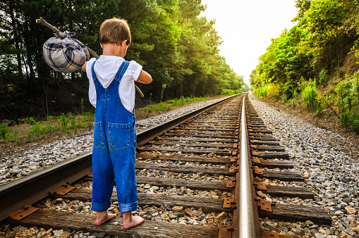 A runaway boy standing on a train track looking down