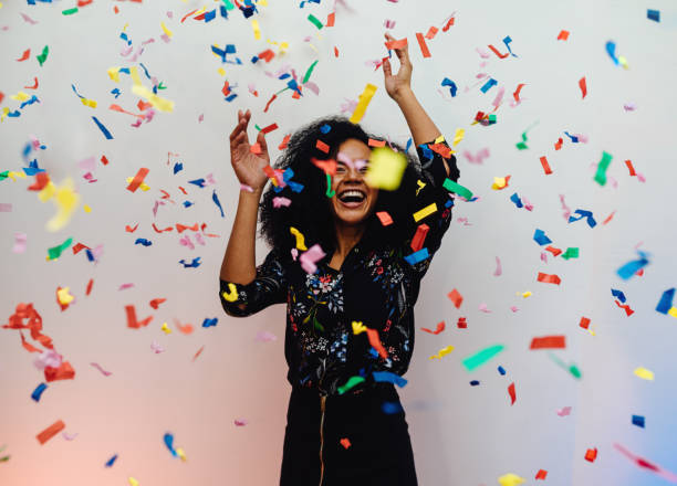 istock Young woman dancing under confetti at home, celebrating birthday 866764832