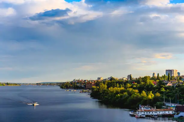 Panoramic view of the right bank from the Voronezh reservoir. Water, lake, boat, dock, city with trees and houses in sunset time
