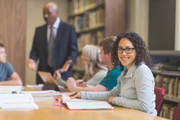 istock College students study together in the university library. An African American professor is helping them. 866793170