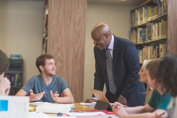 istock College students study together in the university library. An African American professor is helping them. 866793172