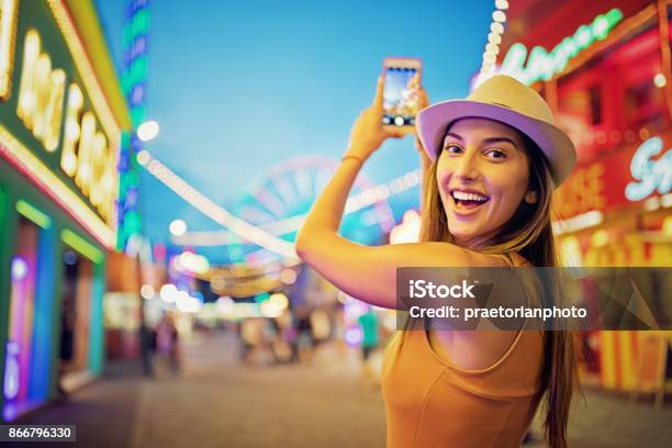 Happy Girl Is Taking Pictures With Her Mobile Phone In A Funfair Stock Photo - Download Image Now