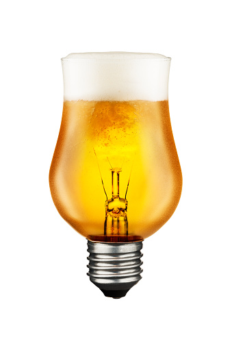 Cold beer into glowing tungsten light bulb isolated in white background with clipping path