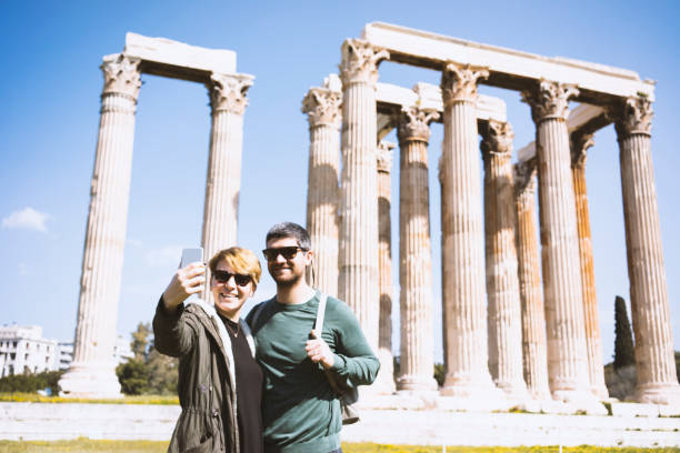 туристическая пара делает селфи в храме олимпийского зевса - vacations photographing brown hair 30s стоковые фото и изображения
