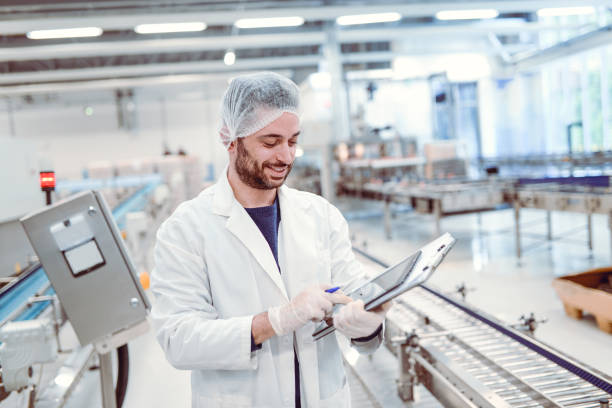 istock Young Handsome Smiling Scientist With Clipboard Posing in Factory 866816870