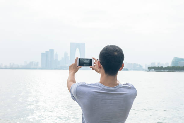 istock man standing on waterfront and taking shots with smartphone 866823112