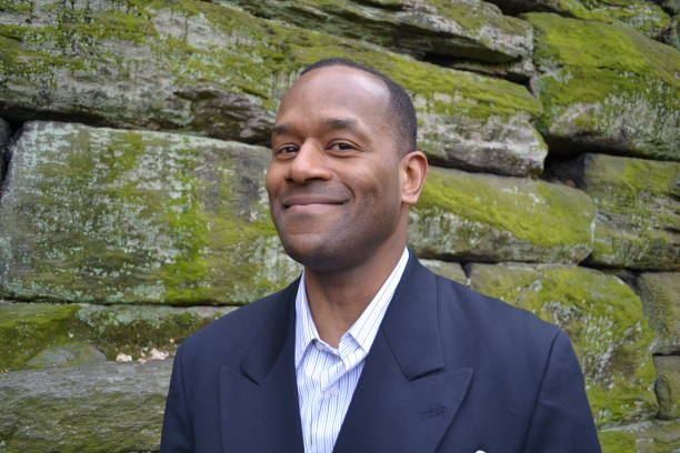 Model happy & smiling wearing a business suit ; brick wall