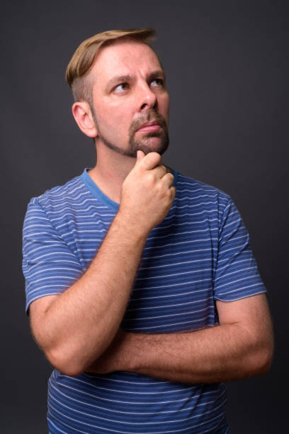 istock Blond goatee bearded man wearing blue striped shirt against gray background 866841020