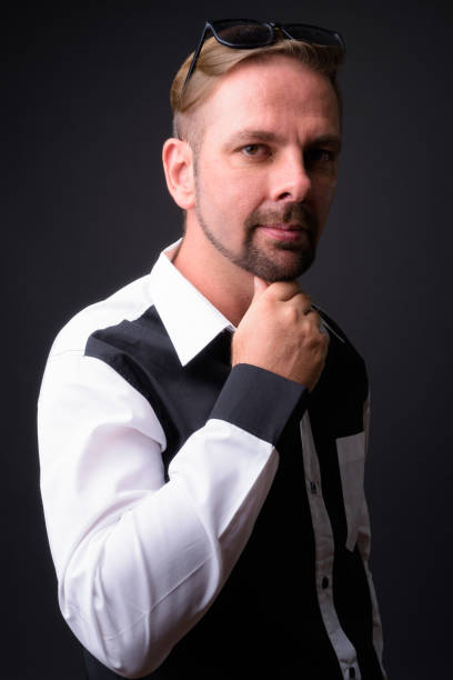 Blond goatee bearded man wearing black and white shirt against gray background