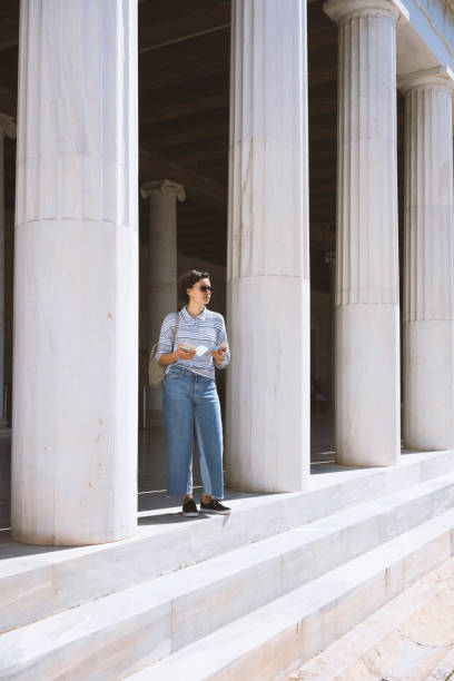 istock Young woman standing by the classic Greek columns 866849602
