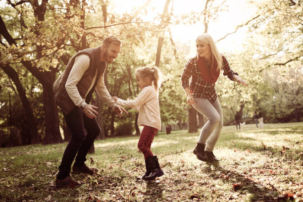 istock Cheerful parents with their little daughter playing in park. 866855986