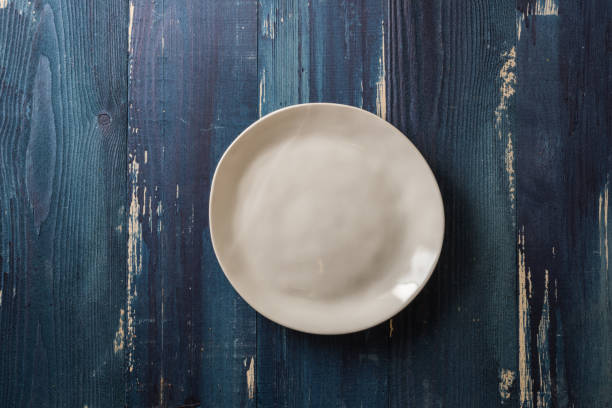 istock Beige Plate on blue wooden background 866859256